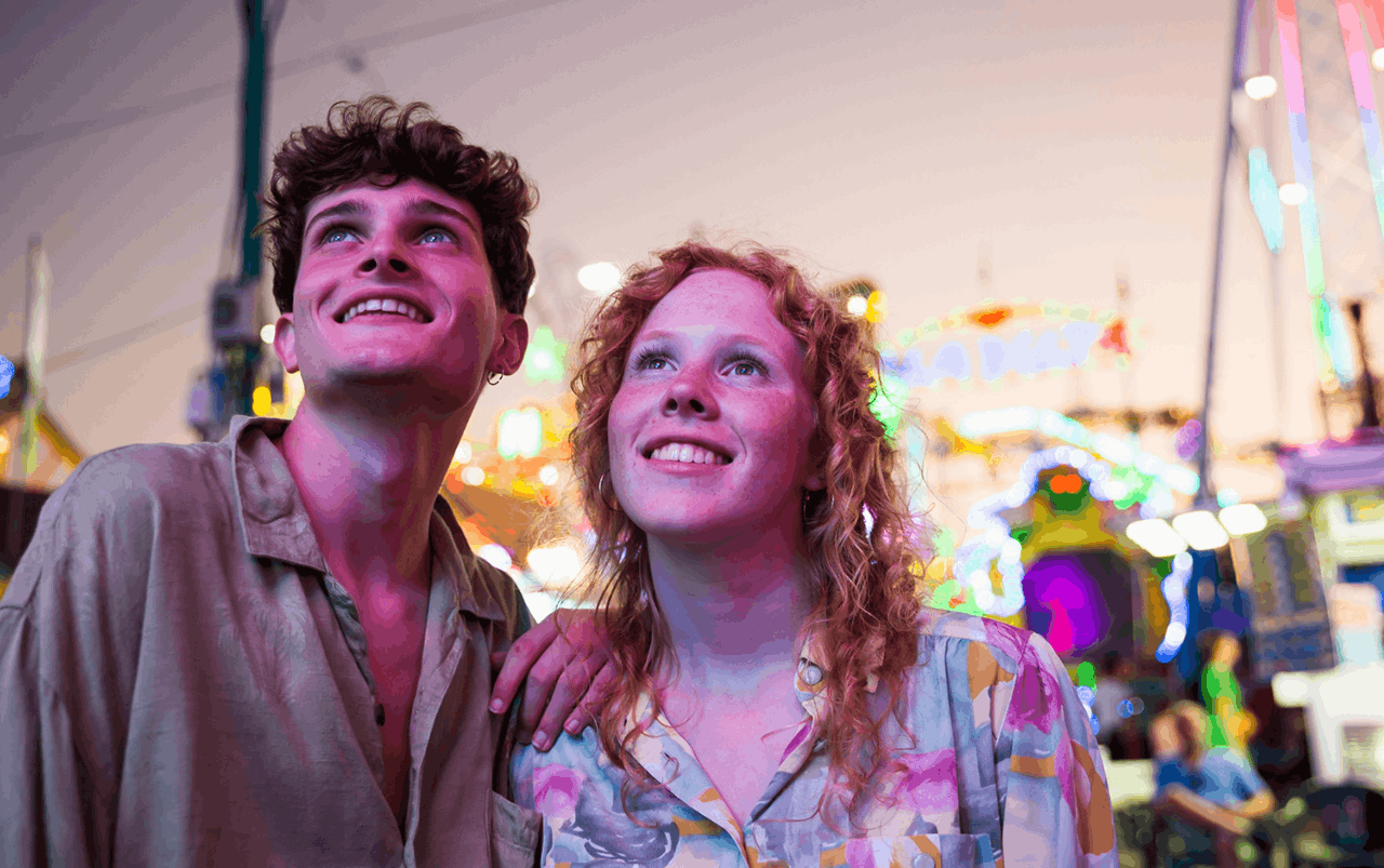 Two young people at a fair in the evening.